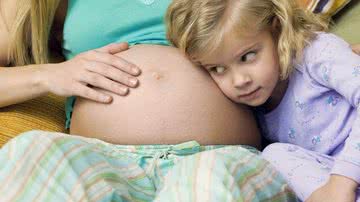 Criança abraçada barriga mãe grávida - Photodisc/Thinkstock